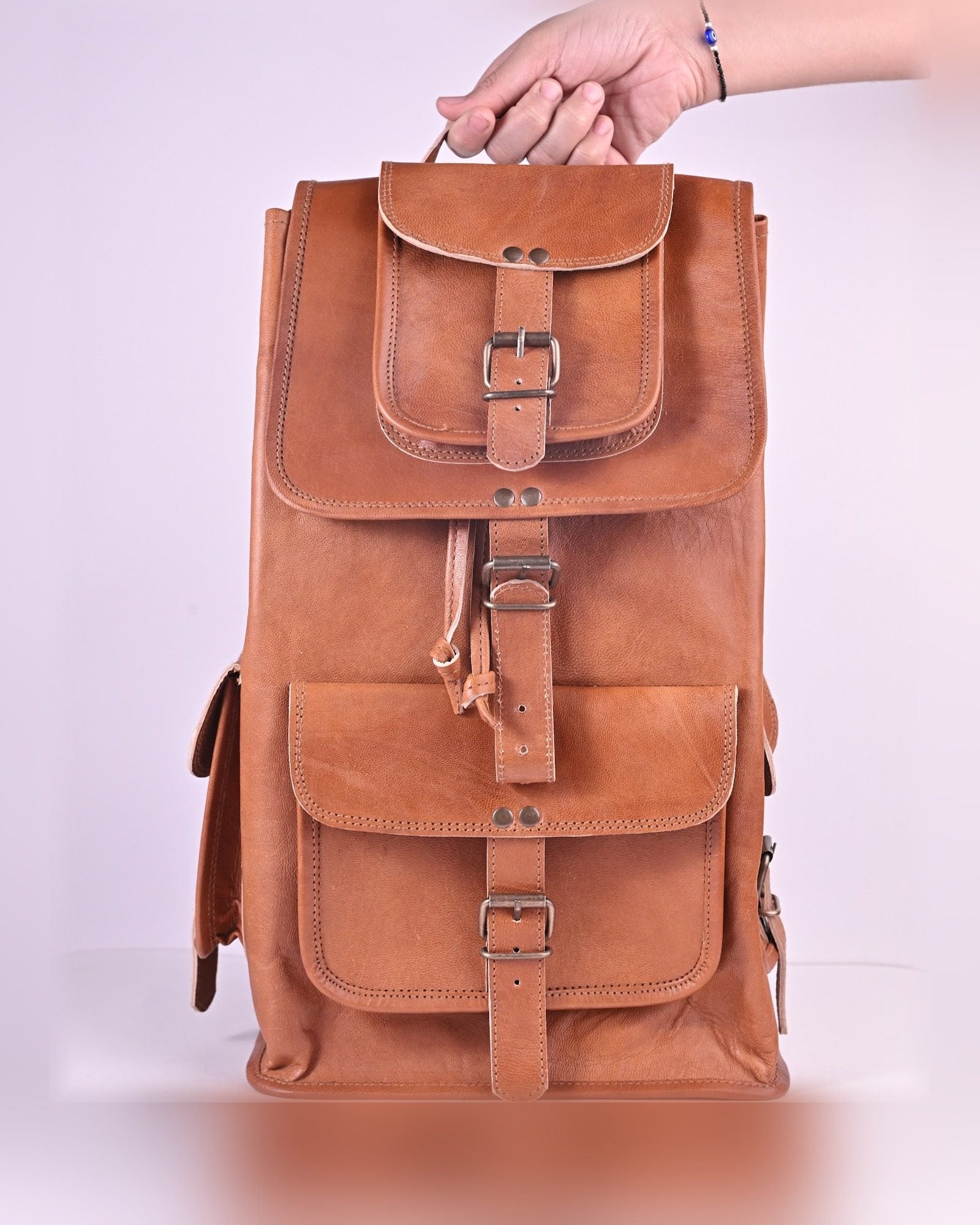 The Aravalli Backpack held by its top handle — true 16 in scale