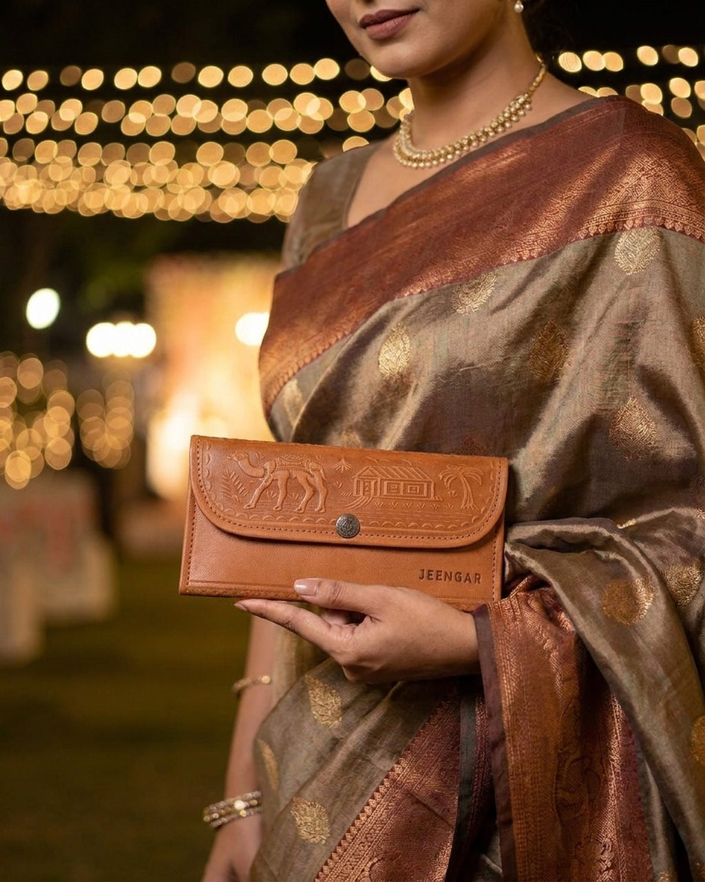 The Gangaur Clutch in Tan held in hand at a festive evening celebration