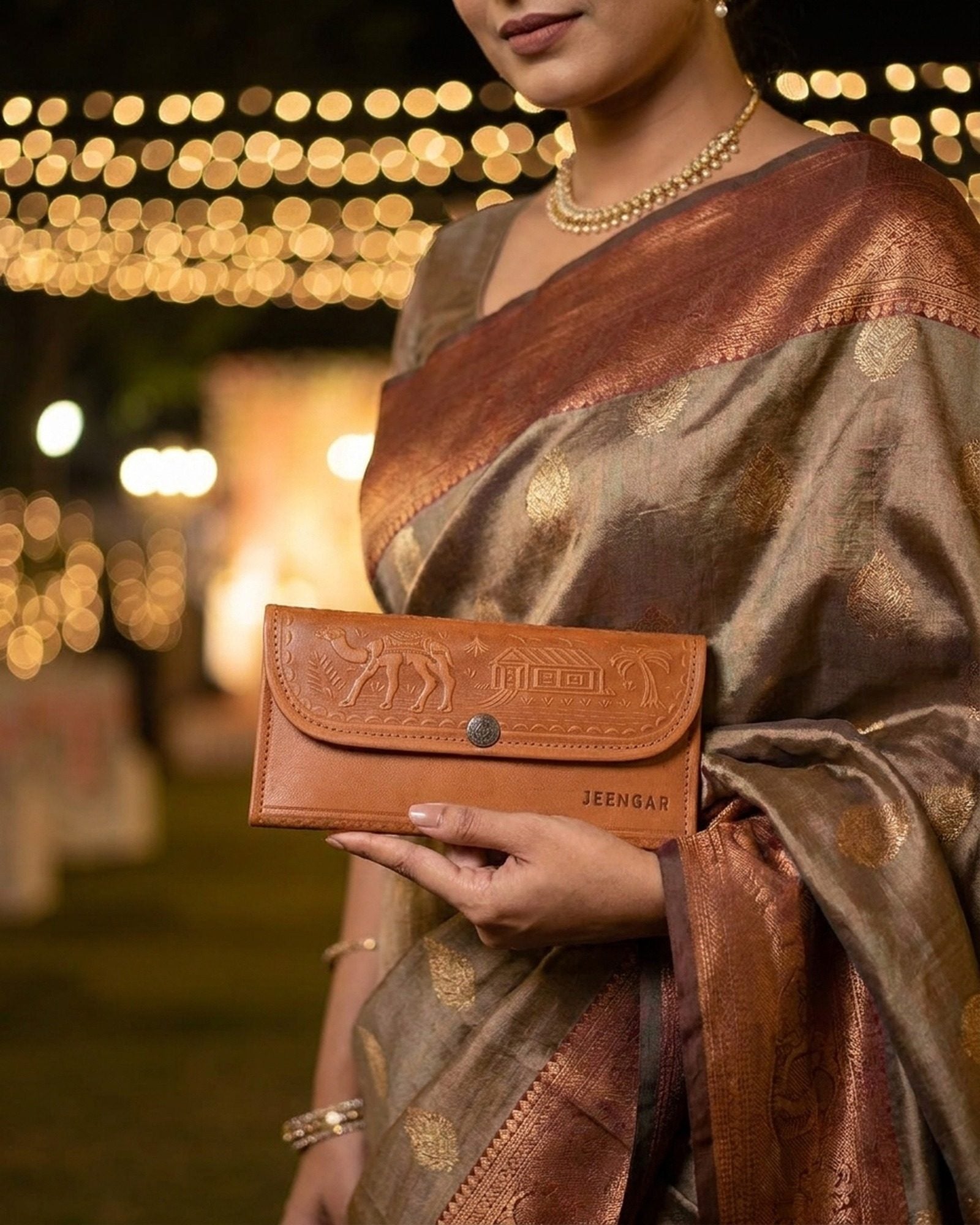 The Gangaur Clutch in Tan held in hand at a festive evening celebration