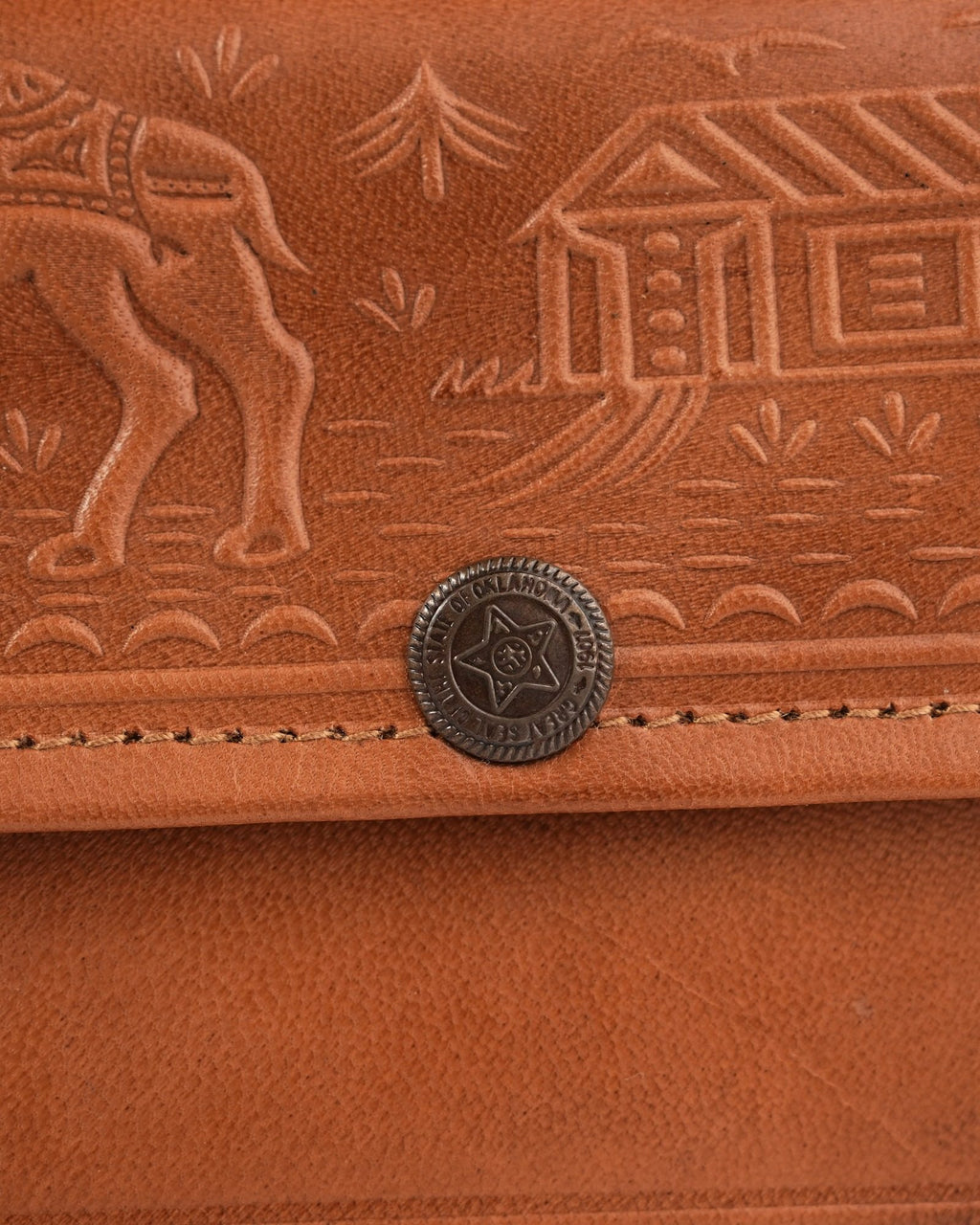 The Gangaur Clutch in Tan — close detail of the hand-embossed camel and dwelling motif