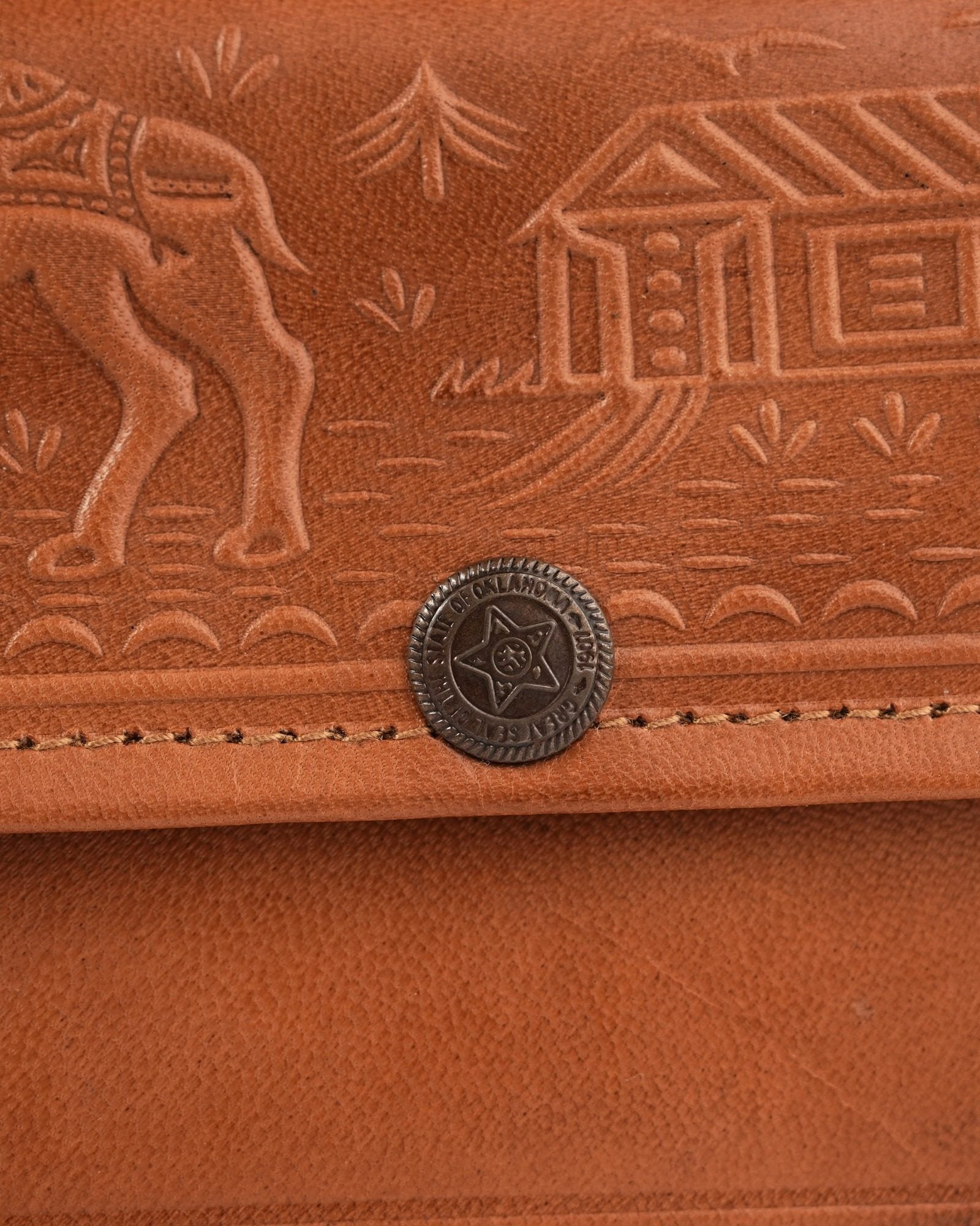 The Gangaur Clutch in Tan — close detail of the hand-embossed camel and dwelling motif