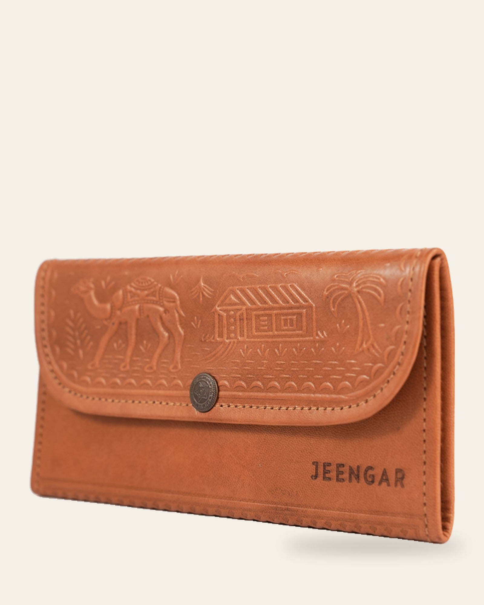 The Gangaur Clutch in Tan — three-quarter view with antique concho and JEENGAR stamp