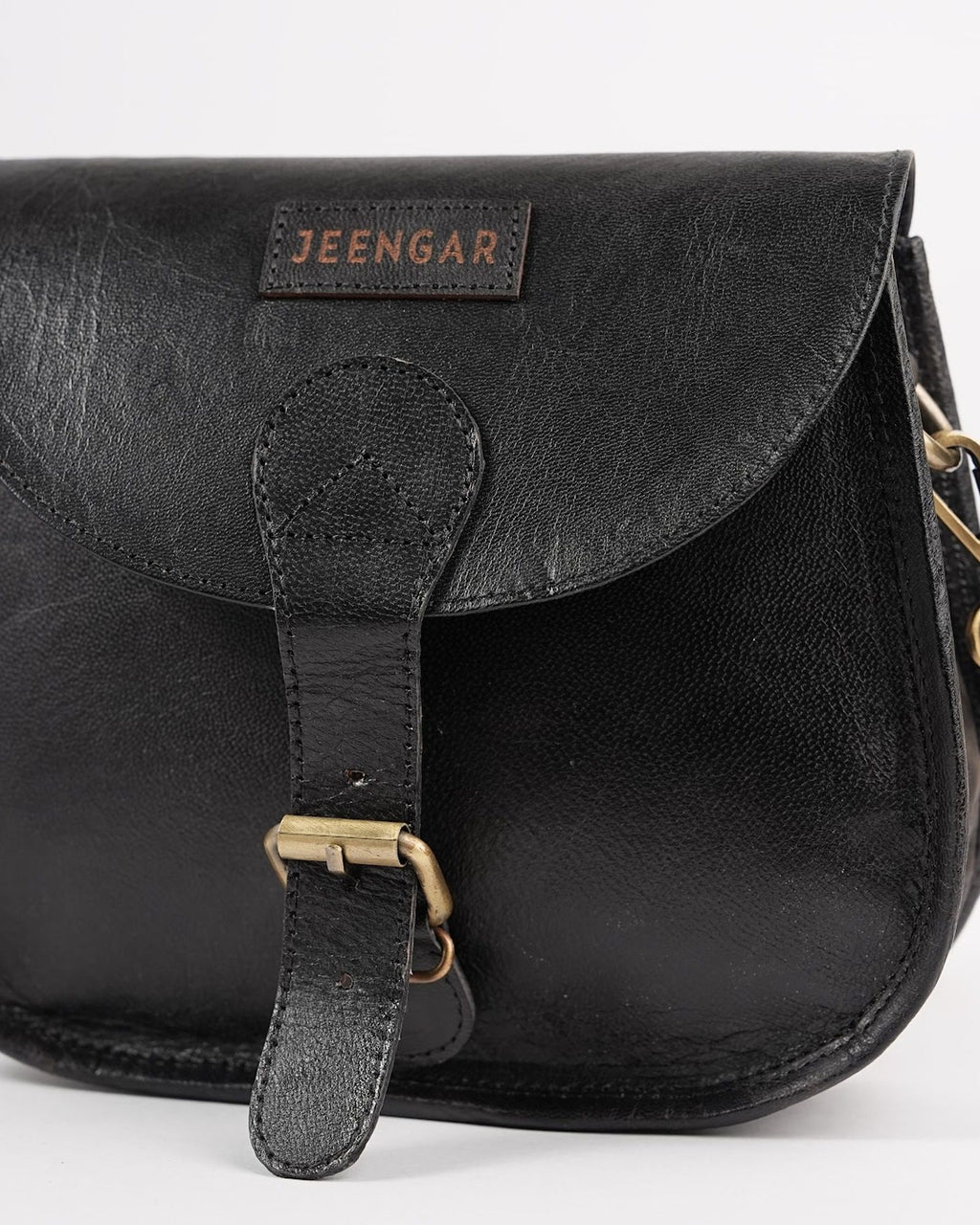 The Marwari Sling in Black — stitched Jeengar label and saddle-flap detail