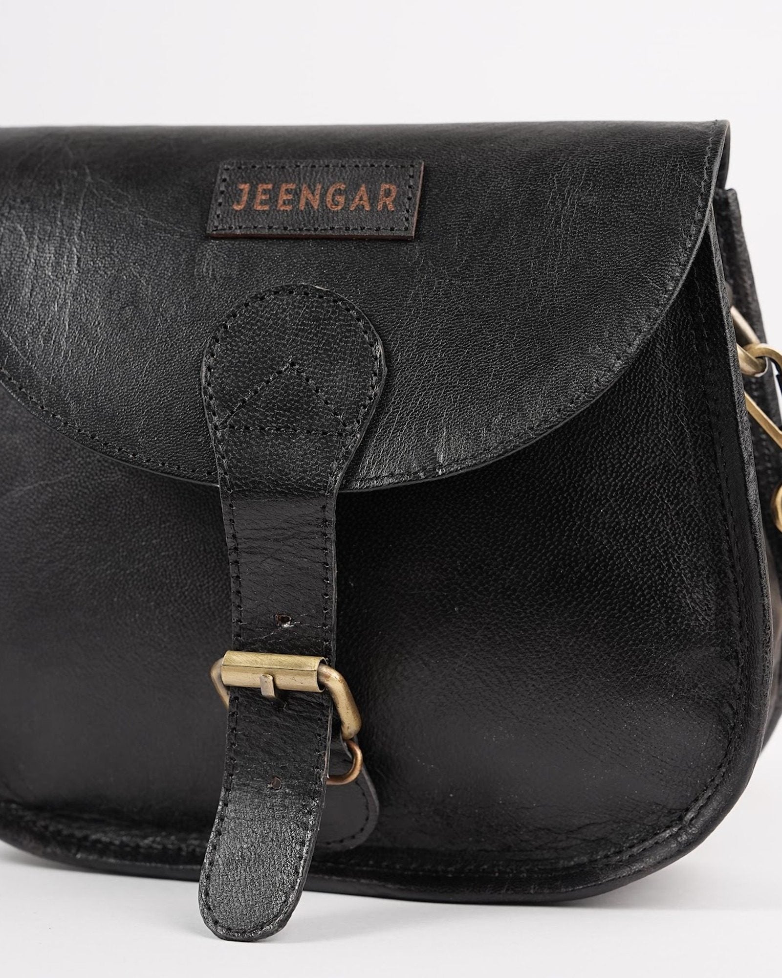 The Marwari Sling in Black — stitched Jeengar label and saddle-flap detail