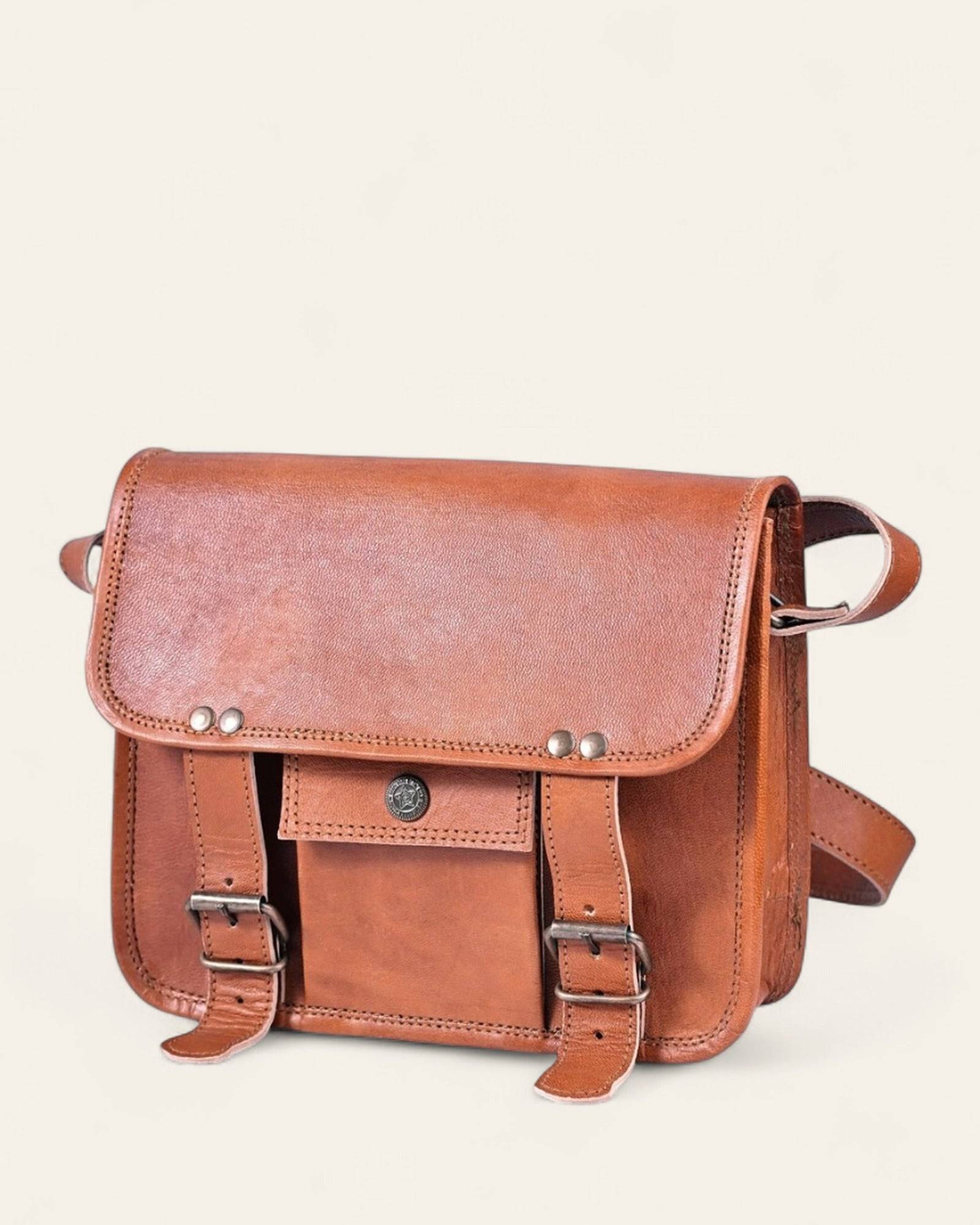 The Jaigarh Sling in natural certified leather, front view with twin buckle straps and antique-brass concho