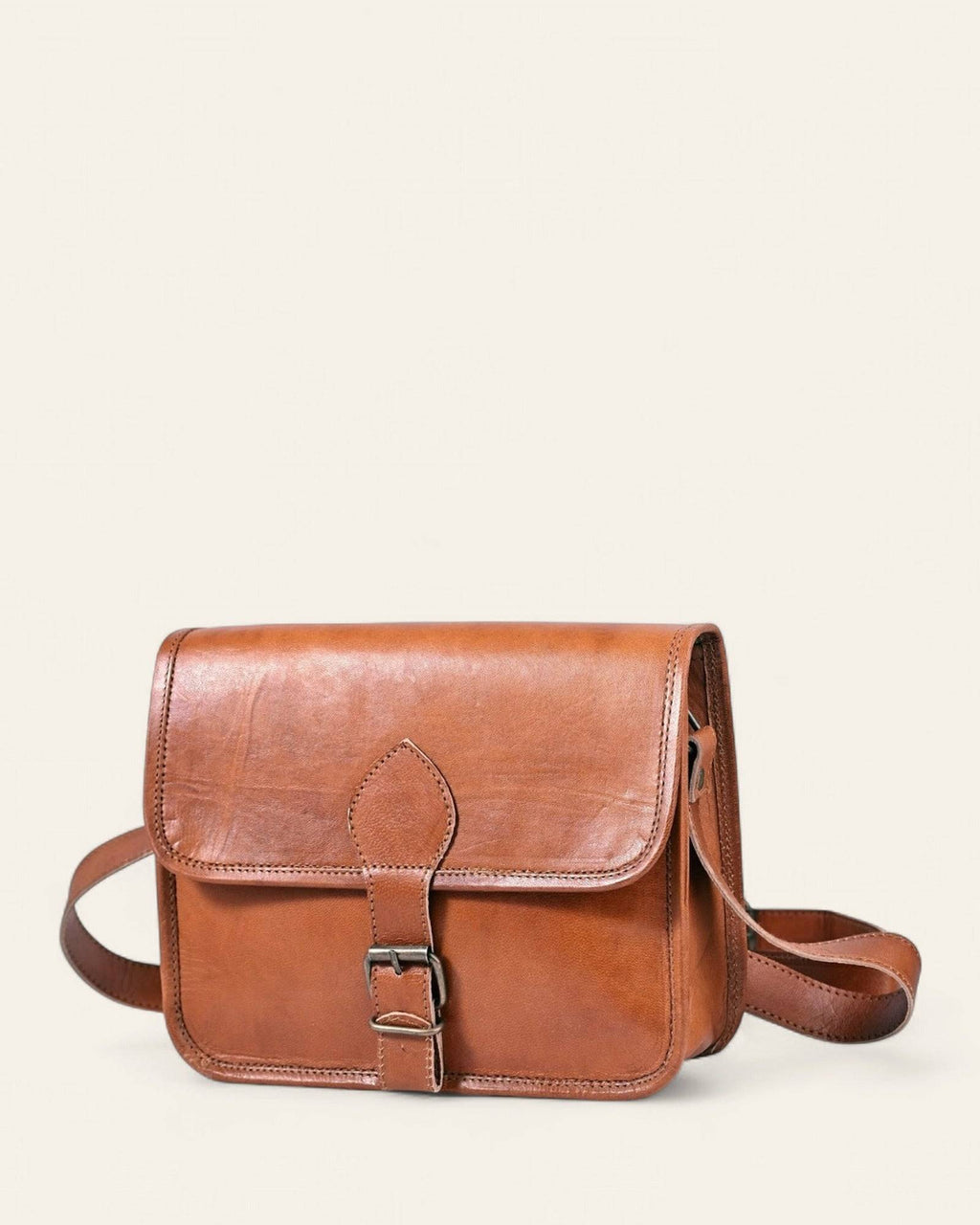 The Runicha Sling in natural-brown certified real leather — front view with buckle-strap flap