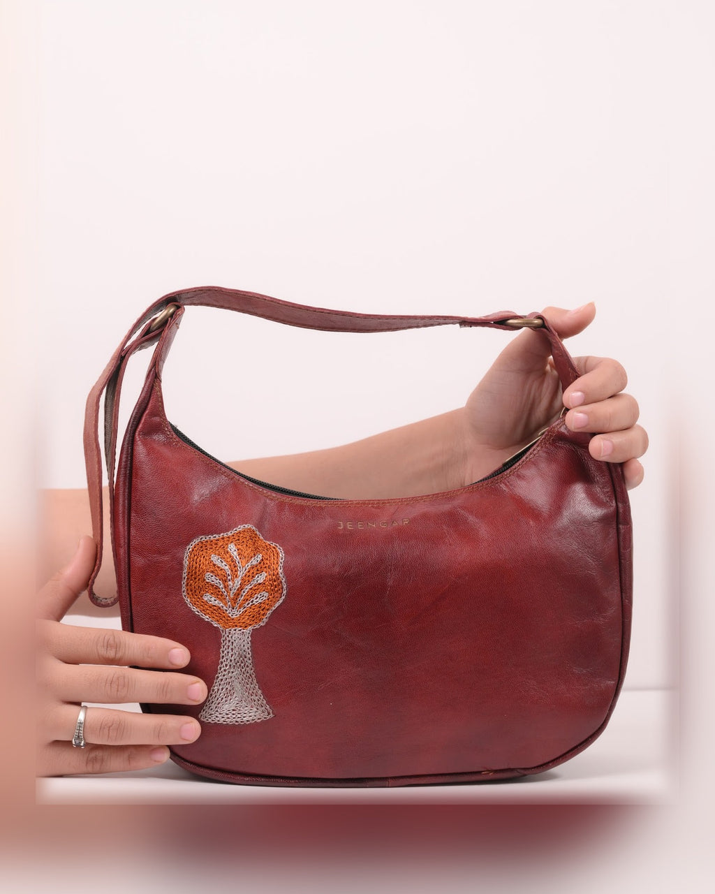 The Kashida Shoulder Bag Padmini in Cherry held in hand