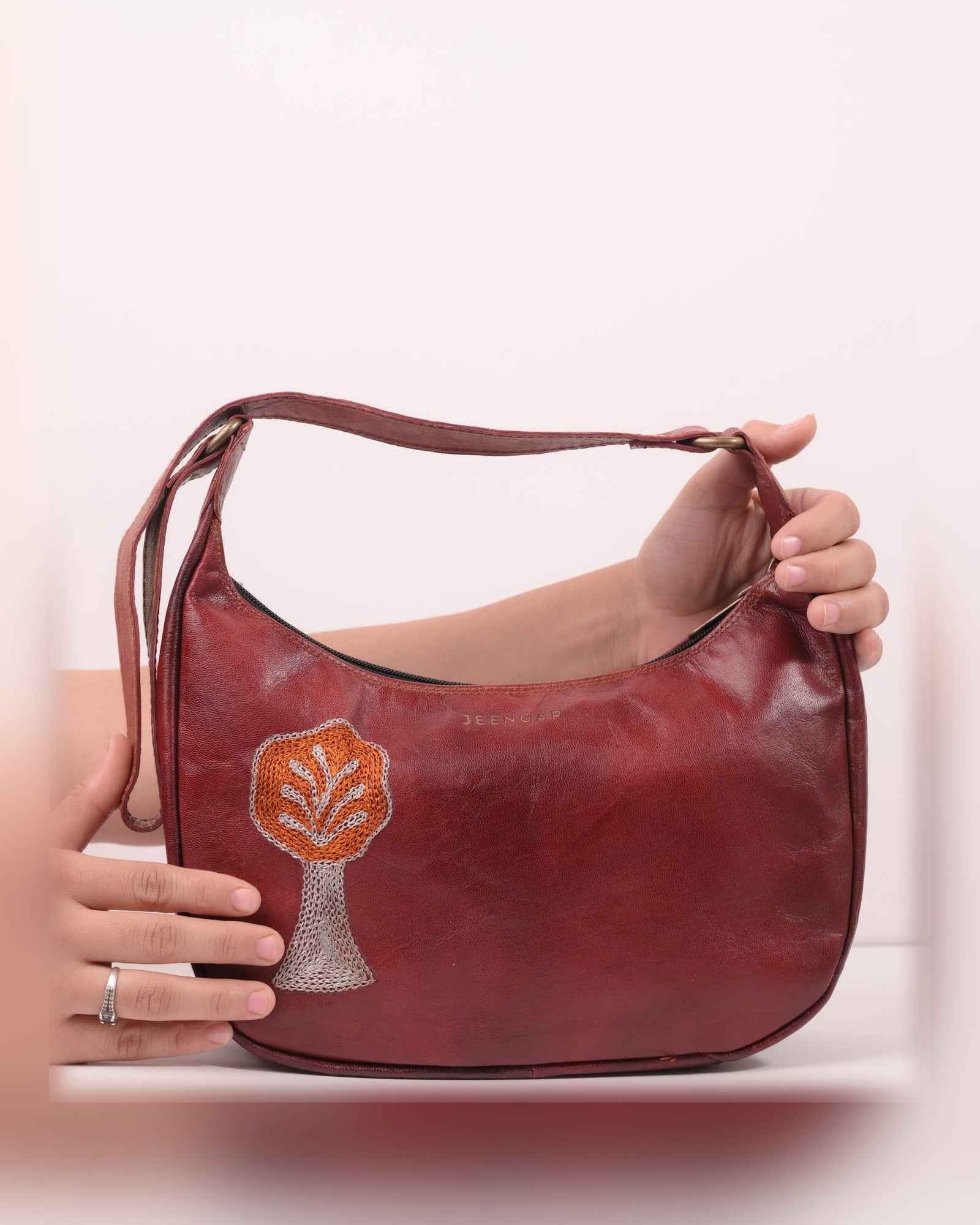 The Kashida Shoulder Bag Padmini in Cherry held in hand