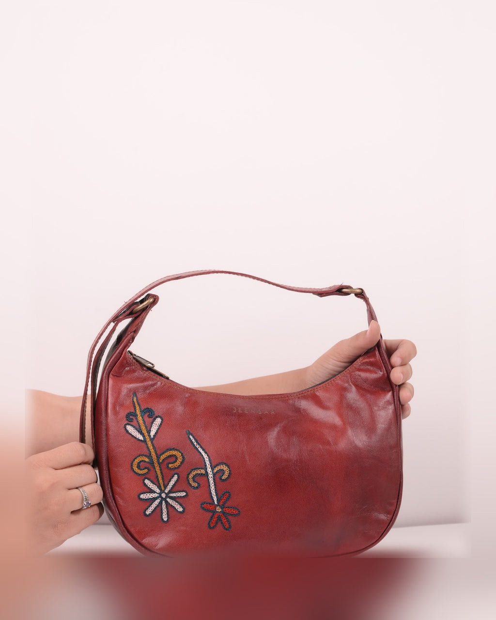 The Kashida Shoulder Bag Mira in Cherry held in hand