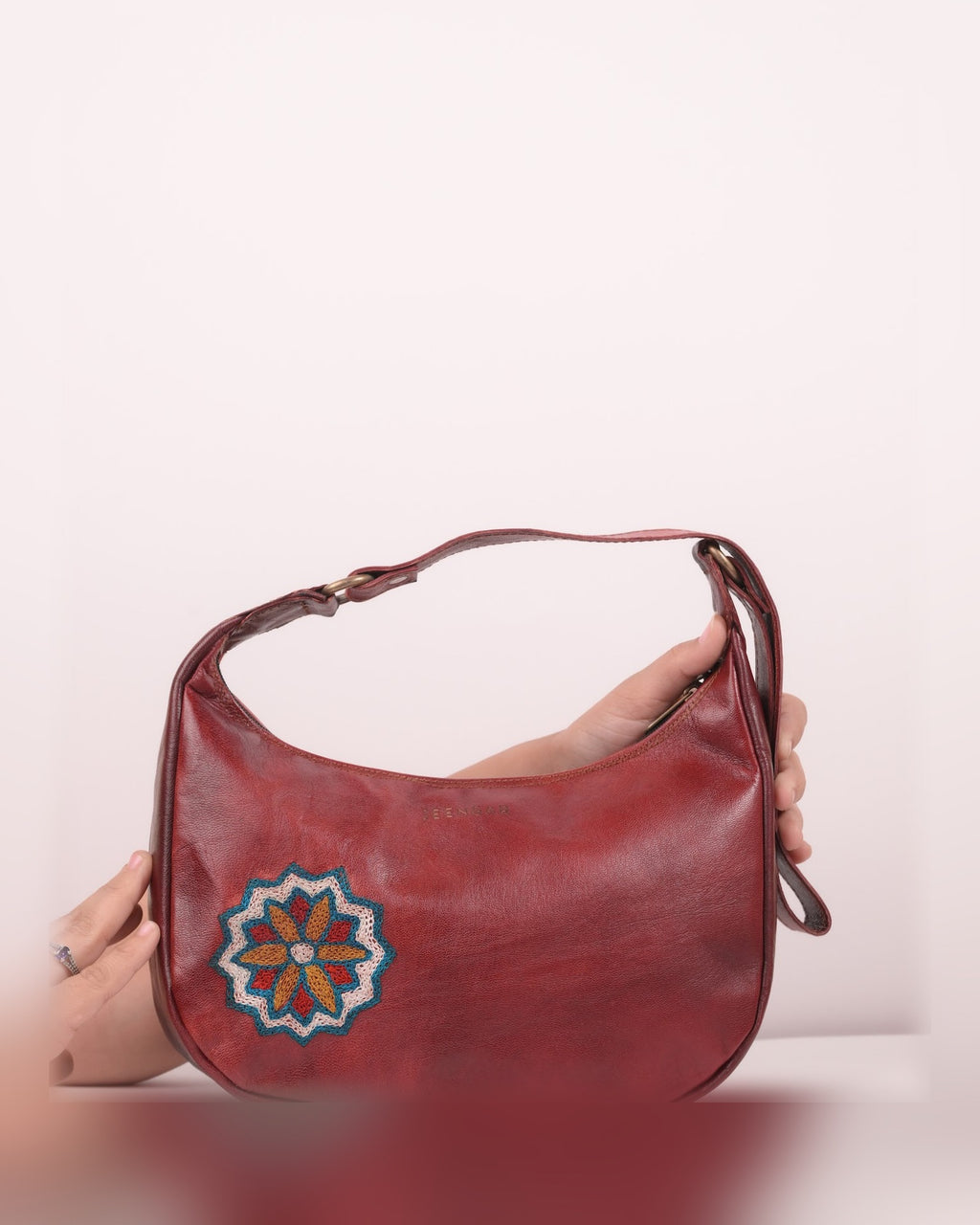 The Kashida Shoulder Bag Hadi in Cherry held in hand