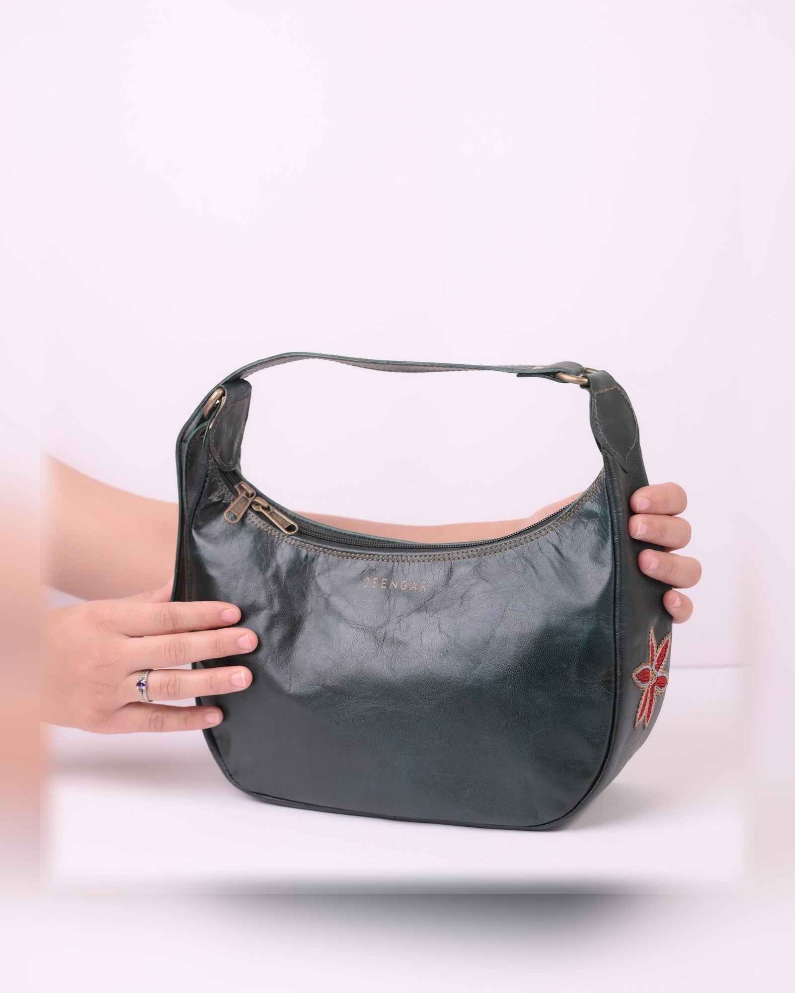 The Kashida Shoulder Bag Moomal in Dark Olive held in hand