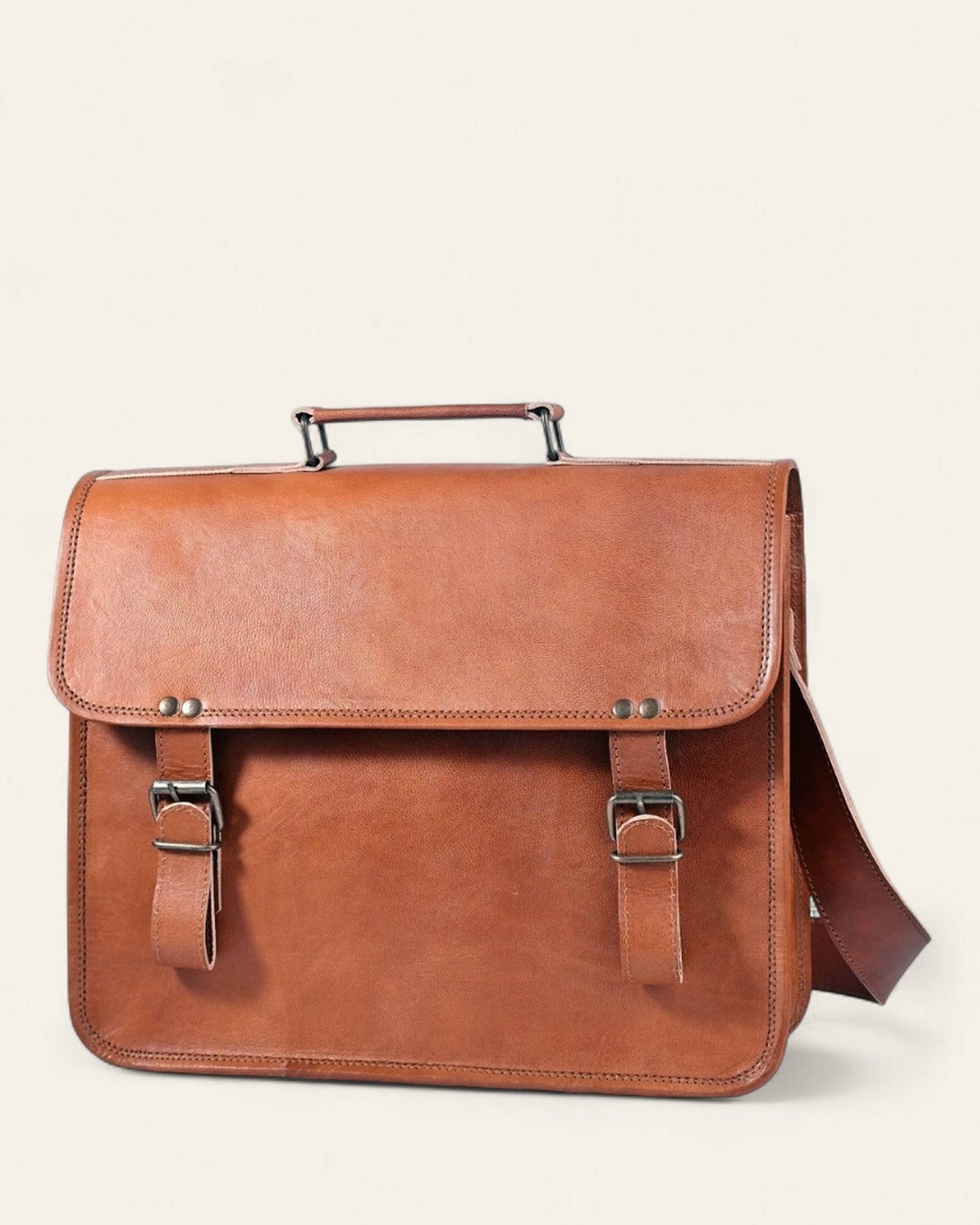 The Ajmer Laptop Bag in natural certified leather, clean pocket-free front with twin buckle straps and top handle