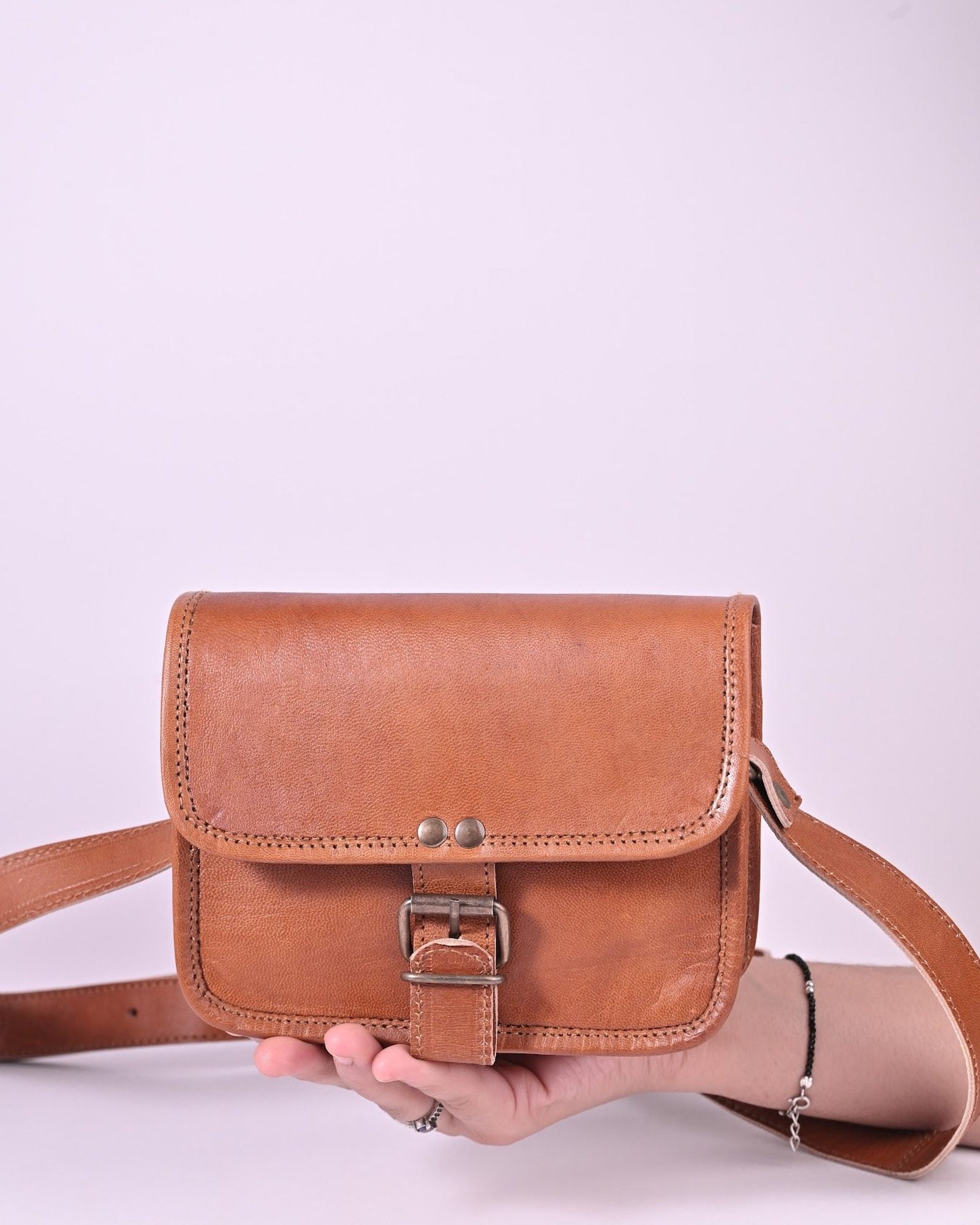 The Alwar Mini Satchel held in hand — compact palm-sized scale